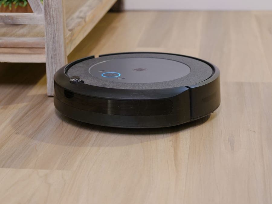 A robot vacuum crossing a wooden floor