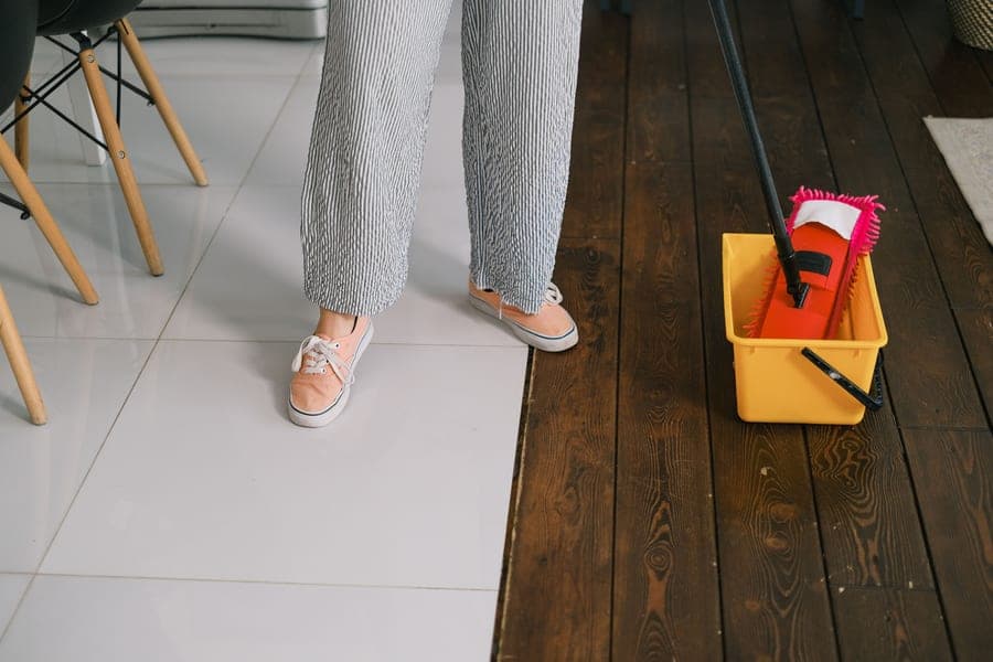 A steam mop being pushed across a tiled floor