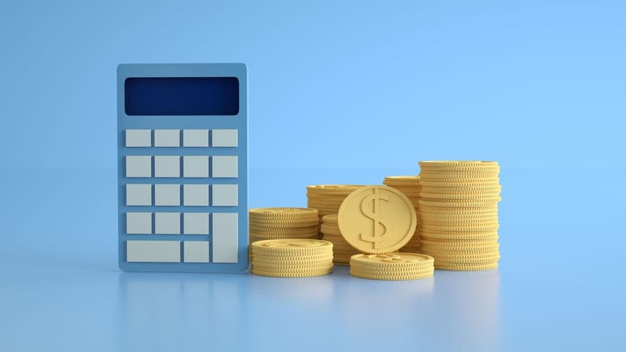 Stacked coins beside a calculator on a neutral surface